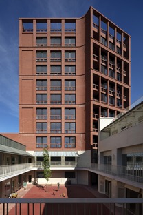 Torre di appartamenti con scuola in mattoni, cemento e legno